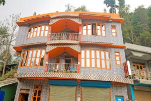 an orange building with windows and a balcony at Flagship Jwajalapa Homestay in Kalimpong