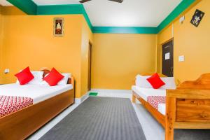 two beds in a room with yellow walls and red pillows at Flagship Jwajalapa Homestay in Kalimpong