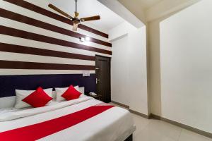 60800 Hotel Landlord في Rohtak: غرفة نوم بسرير كبير ومخدات حمراء