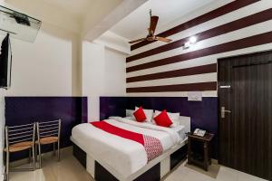 60800 Hotel Landlord في Rohtak: غرفة نوم بسرير ومخدات حمراء وبيضاء