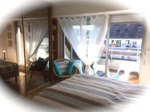 a bedroom with a bed and a large window at LE GALION in La Baule