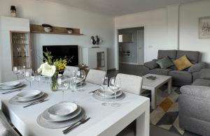 Apartamentos Maria de Lucia- Ático في Arou: غرفة معيشة مع طاولة بيضاء مع كؤوس للنبيذ