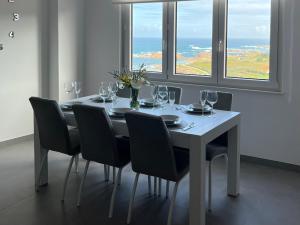 een eettafel met stoelen en een tafel met wijnglazen bij Apartamentos Maria de Lucia- Ático in Arou