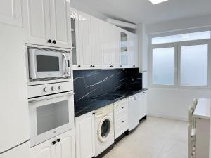 a white kitchen with a microwave and a washer and dryer at Ansar Suite in Torrelavega