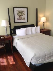 a bedroom with a large white bed with two lamps at The Prytania Oaks in New Orleans