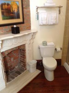 La salle de bains est pourvue d'une cheminée et de toilettes blanches. dans l'établissement The Prytania Oaks, à La Nouvelle-Orléans