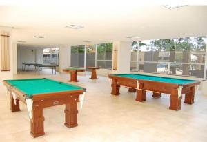 two pool tables in a large room with windows at Veredas do Rio Quente Hotel Service in Rio Quente