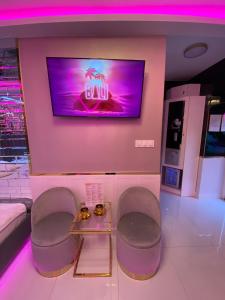 una camera con due sedie e una TV a parete di Apartament "Love Paradise" Centrum z dużą wanną dla Dwojga a Gniezno