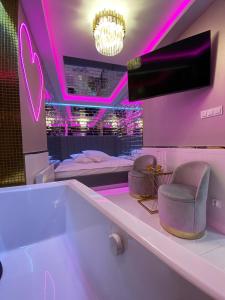 Habitación con iluminación rosa, cama y sillas en Apartament "Love Paradise" Centrum z dużą wanną dla Dwojga, en Gniezno