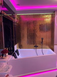 una vasca da bagno bianca in una stanza con luci rosa di Apartament "Love Paradise" Centrum z dużą wanną dla Dwojga a Gniezno