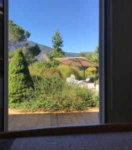 a window view of a garden with an umbrella at Logement classé 4 étoiles avec SAUNA et vue sur le Canigou in Fuilla