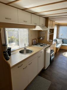 una cocina con fregadero y estufa en Gezellige STACARAVAN met groot, zonnig terras!, en Belt-Schutsloot 17 fotos más