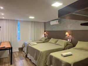 a hotel room with two beds and a window at Chalés Pôr do Sol in Tiradentes