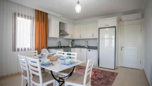 a kitchen with a table with chairs and a white refrigerator at VİLLA TANYERİ in Kas