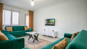 a living room with green couches and a tv at VİLLA TANYERİ in Kas