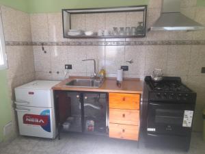 Una pequeña cocina con fregadero y estufa. en Apartamentos km4, en Comodoro Rivadavia 21 fotos más