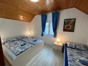 a bedroom with two beds and a window with blue curtains at Apartmaji in Sobe Cuder in Soča