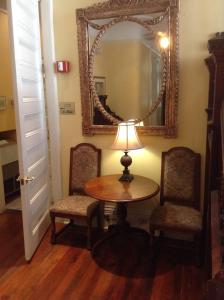 a table and two chairs with a lamp and a mirror at The Queen Anne in New Orleans