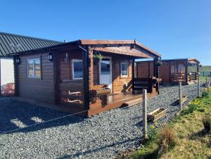 ein Blockhaus mit einer Veranda auf einem Kieshof in der Unterkunft Harlosh Log Cabins in Dunvegan