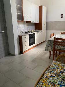 eine Küche mit weißen Schränken, einem Tisch, einem Tisch und einem Tisch in der Unterkunft HomeSea Trapani in Trapani