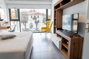 a bedroom with a flat screen tv and a yellow chair at Zoes Apartment Kos Town in Kos