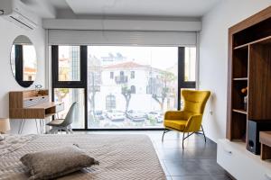 una camera da letto con sedia gialla e scrivania di Zoes Apartment Kos Town a Città di Kos
