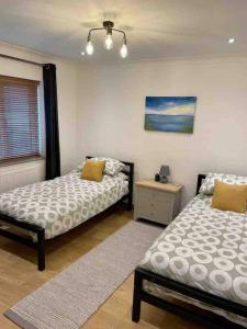 a bedroom with two beds and a table and a window at Modern Coastal 2 Bedroom Home to Relax and Unwind in Heacham