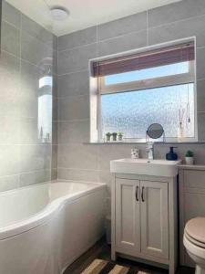 a bathroom with a tub and a sink and a toilet at Modern Coastal 2 Bedroom Home to Relax and Unwind in Heacham