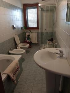 een badkamer met 2 toiletten, een wastafel en een douche bij Casa Vacanze La Notte in Spello