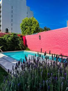 a swimming pool with purple flowers in front of a pink wall at Yunga in Salta