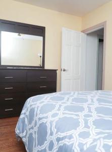 Schlafzimmer mit einem Bett und einer Kommode mit einem TV in der Unterkunft Raised bungalo in Toronto