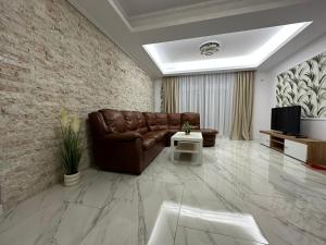 Una sala de estar con un sofá de cuero y un televisor. en Golden Garden Luxury Apartment in Bucharest, en Bucarest