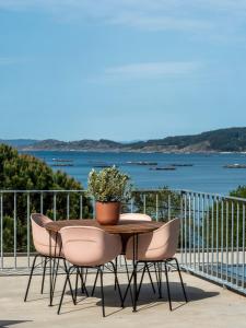 a table with chairs and a potted plant on a balcony at INSUA BEACH HOUSE in Pontevedra