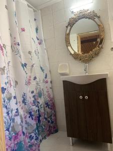 łazienka z umywalką, lustrem i zasłoną prysznicową w obiekcie Jimmy's Crib w mieście Moúdhros