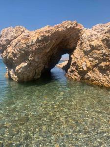 an arch in a rock formation in the water at Jimmy's Crib in Moúdhros +4 photos