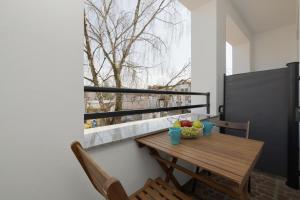 a wooden table and chairs on a balcony with a window at Apartament LENA Dziwnówek nad morzem in Dziwnówek