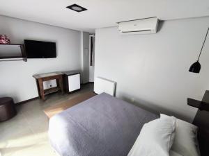 a bedroom with a bed and a flat screen tv at Pousada Das Araucarias in Canela