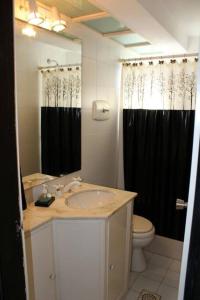 uma casa de banho com um lavatório, um WC e uma cortina de duche preta. em Torre Marfil piso 12 em Punta del Este