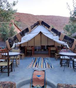 a tent with tables and chairs and a rug in front at Dar Isselday in Tisseldeï