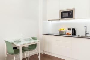 a white kitchen with a small table and chairs at El Sol,10 in Las Lagunas
