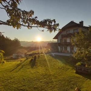a house on a hill with the sun in the background at SCHWEIZER Hof in Tamsweg