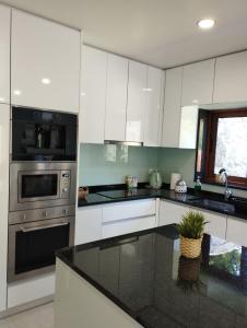 a kitchen with white cabinets and a black counter top at Quinta da Casa Matilde - NATURE HOUSE in Geres