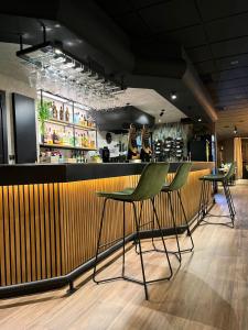 a bar with two green chairs in a restaurant at Pensión Quilmes in Vimianzo