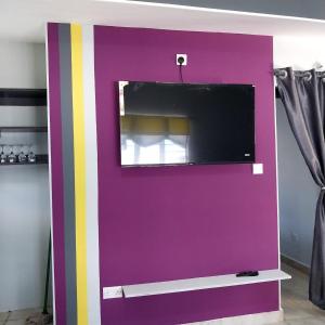 a purple wall with a tv on top at Bedroom Diani Beach in Galu