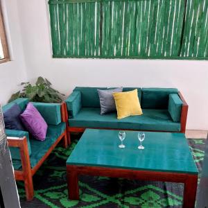 a living room with a green couch and two wine glasses at Bedroom Diani Beach in Galu