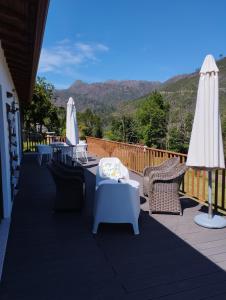 eine Terrasse mit Tischen, Stühlen und einem Sonnenschirm in der Unterkunft Quinta da Casa Matilde - NATURE HOUSE in Geres