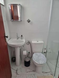 Baño blanco con aseo y lavamanos en Loft no Cond. Mata Atlântica en Volta Redonda