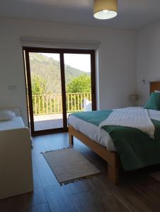 een slaapkamer met een bed en een groot raam bij Quinta da Casa Matilde - NATURE HOUSE in Geres