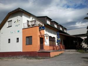 um edifício branco e laranja com uma varanda em Hostinec Banik em ľubeľa