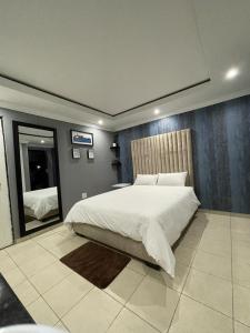 1 dormitorio con 1 cama grande y espejo en Yello guest house, en Vanderbijlpark